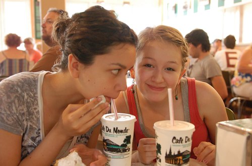 The girls sipping on sodas with their beignets at Cafe Du Monde