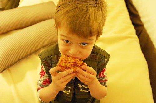 Adam snacking away on some late night hotel room pizza. He LOVES his Yellowstone Ranger vest, and even slept with it close by.